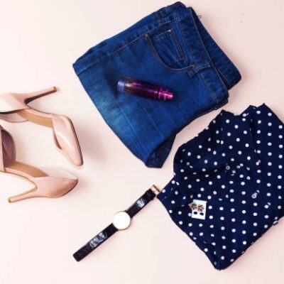 blue blouse and blue jeans, hand watch, earrings, pink heels, perfume bottle. Women's spring summer basic outfit. Apparels flat composition