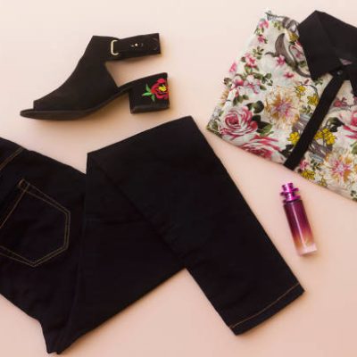 flat lay woman  clothes and accessories collage with summers flower embroidery sandal, black jeans,floral shirt,perfume